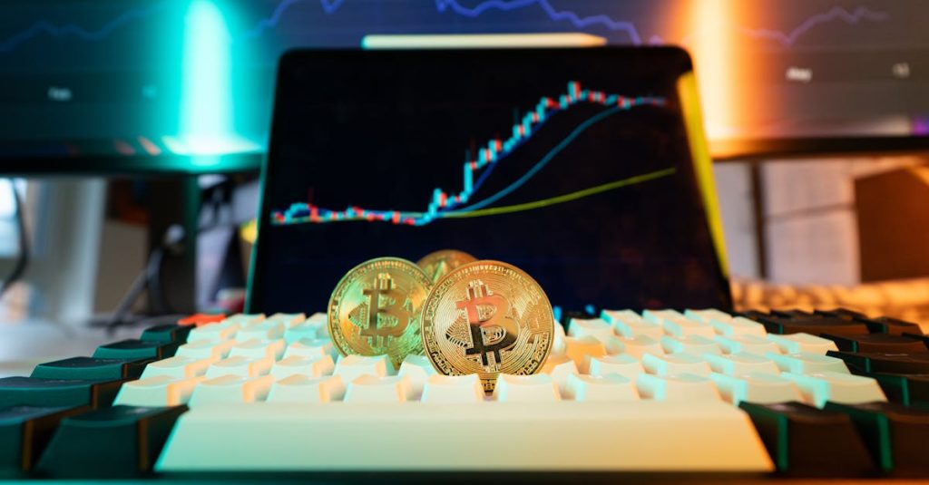 Close-up of Bitcoin coins on a keyboard with a trading chart in the background
